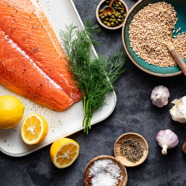 Salmon and lemons on plate next to other ingredients